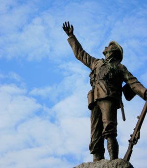 Broze WW1 soldier statue atop a plinth with his open hand and face to the sky