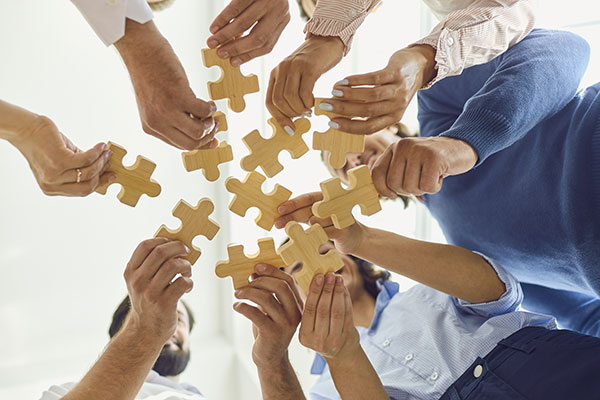 People holding jigsaw puzzle pieces viewed from under